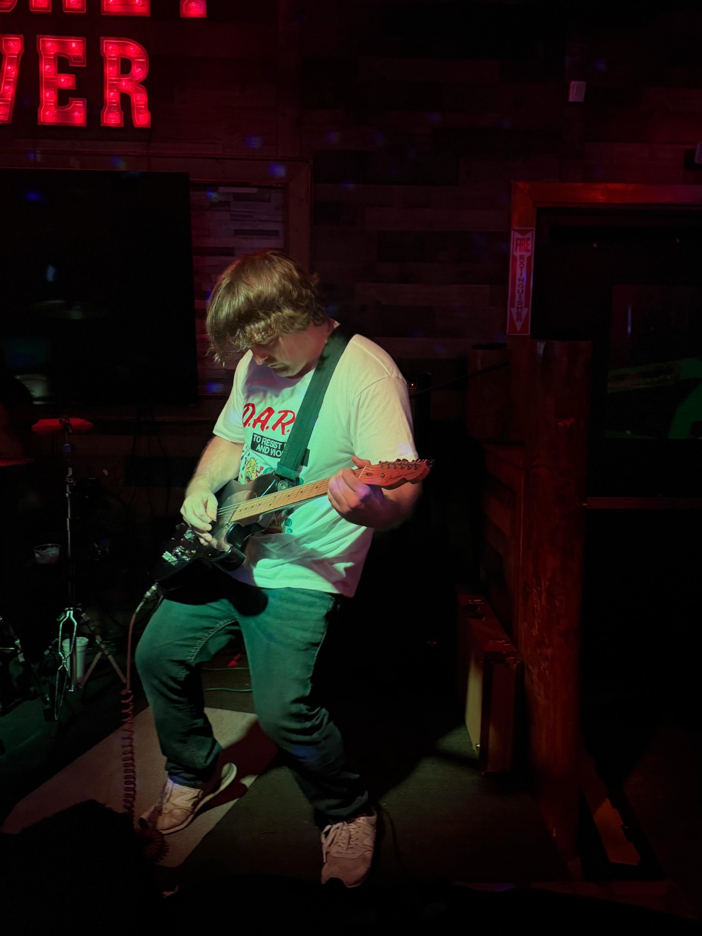 Guitarist locked in under red neon lights