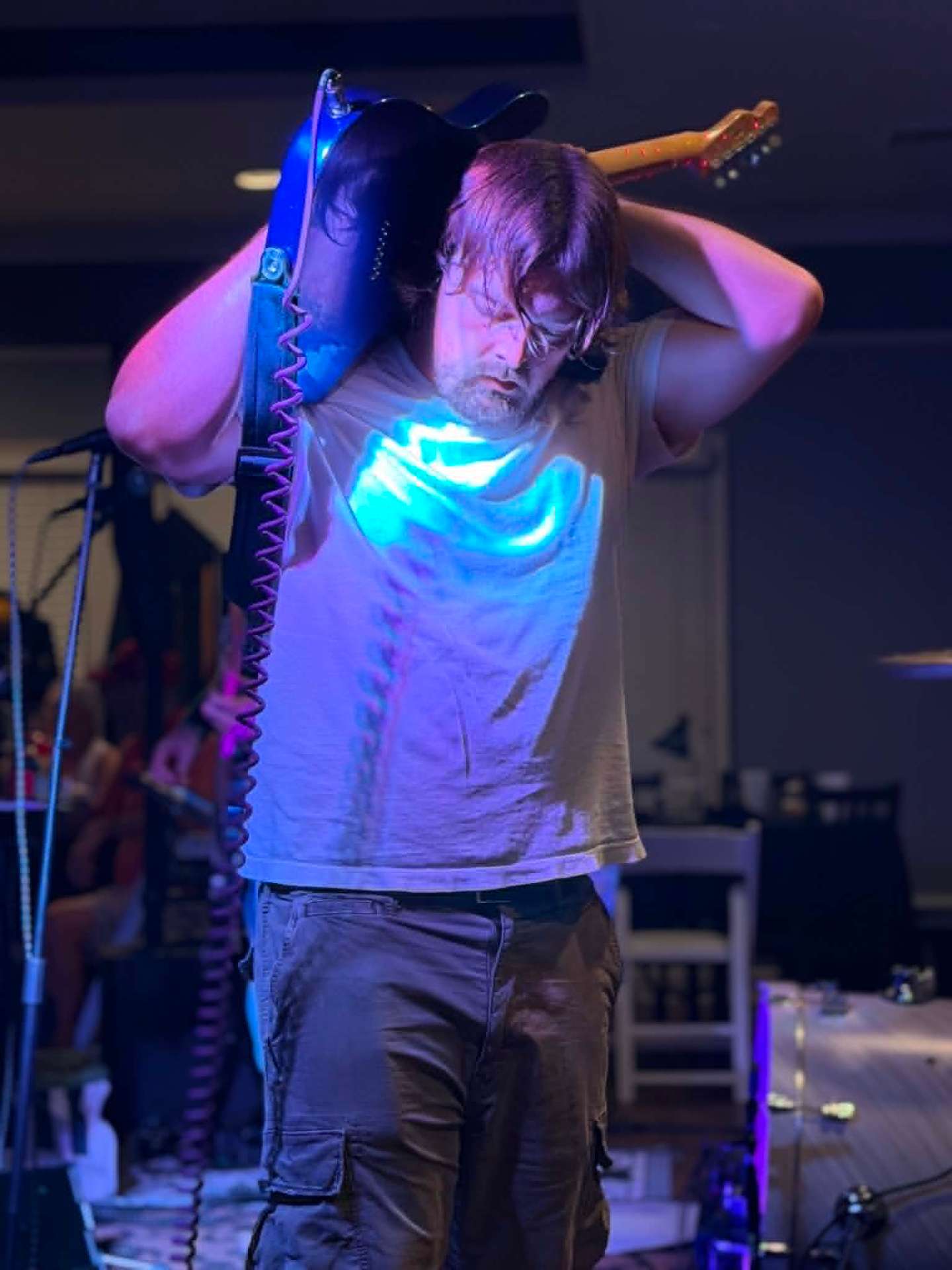 Jesse Mathis with guitar overhead in blue light